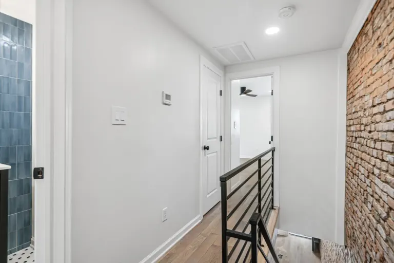 The upper hallway, brick, and black stair railing
