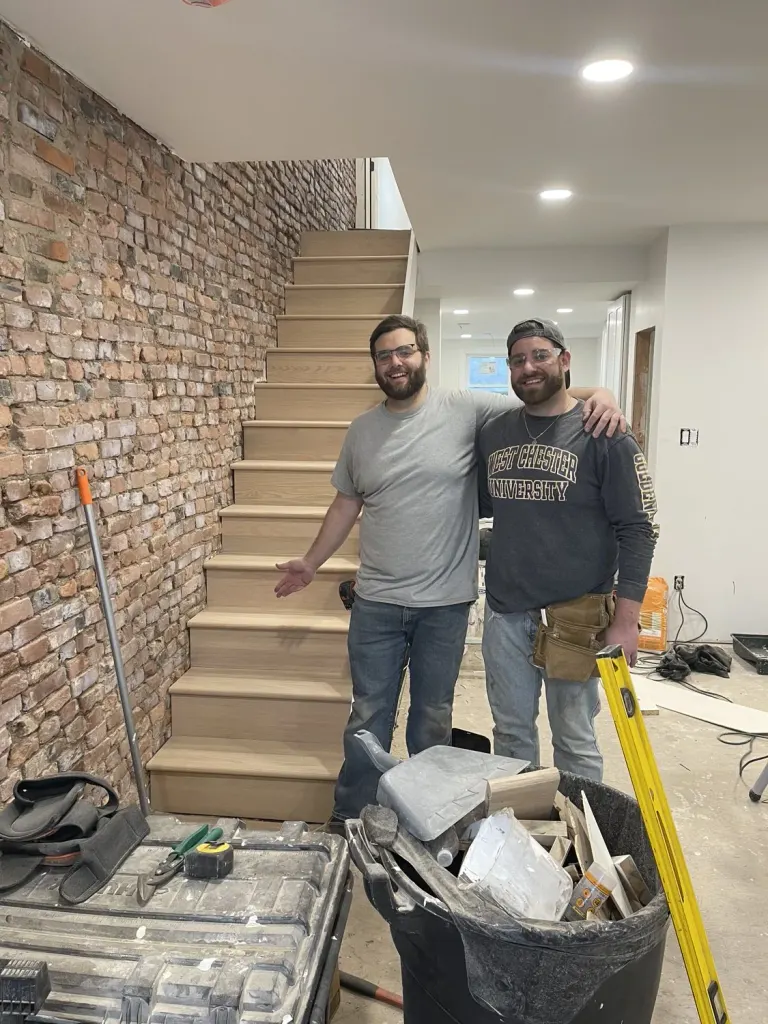 Two crew members in the living space during work on the staircase.